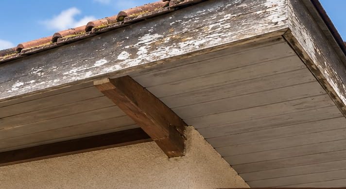 Avant : planche de rive en bois grisé, peinture écaillée