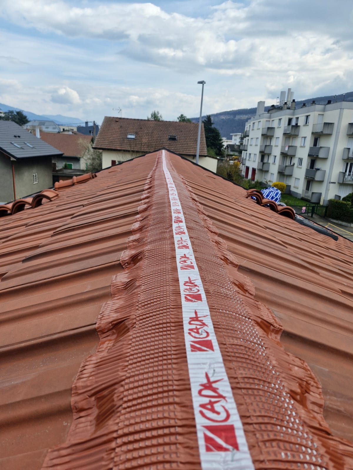 Bande d'étanchéité neuve déroulée le long du faîtage.