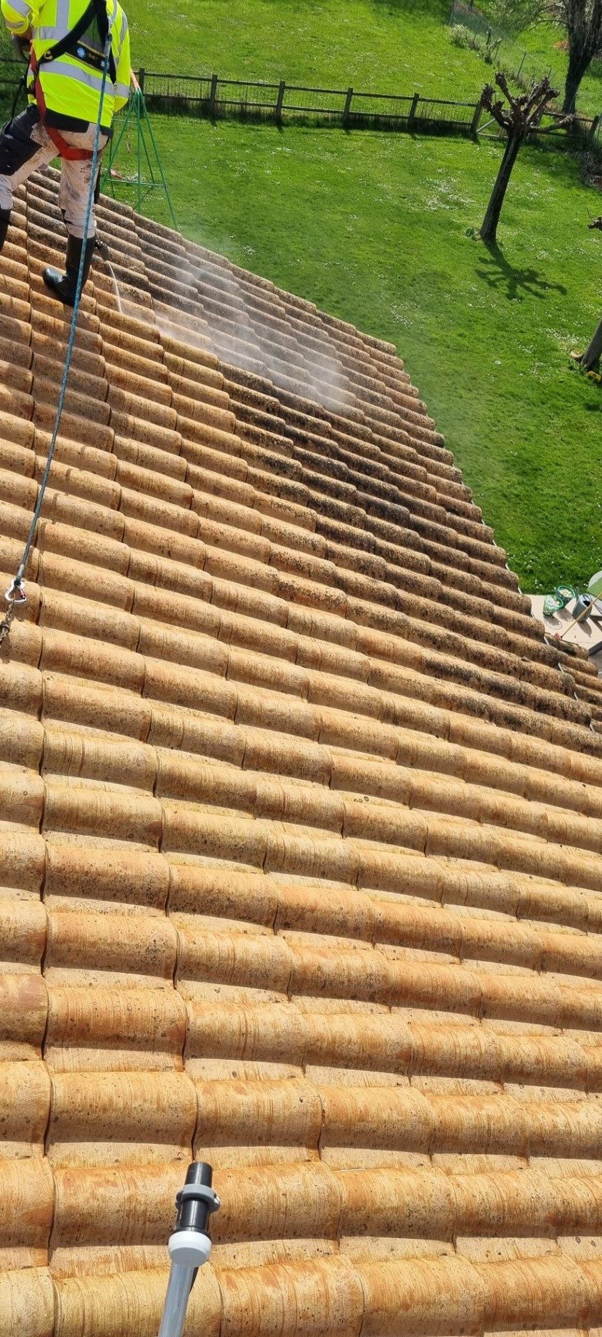 Lavage d'un pan de tuiles en cours, vu depuis le faîtage.